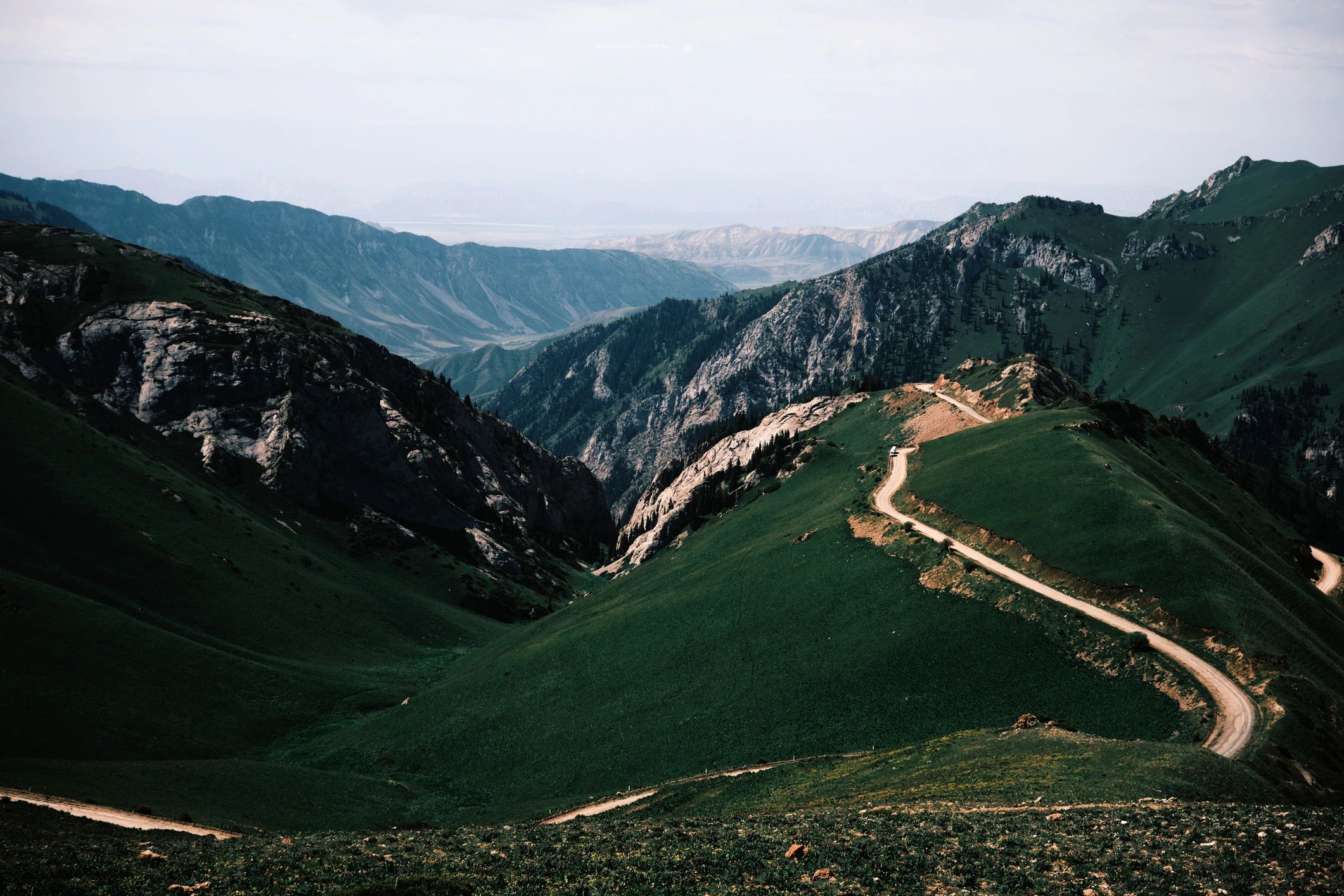 Wide shot summer landscape with winding road to mountain pass
